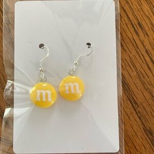 Yellow M&M candy earrings.